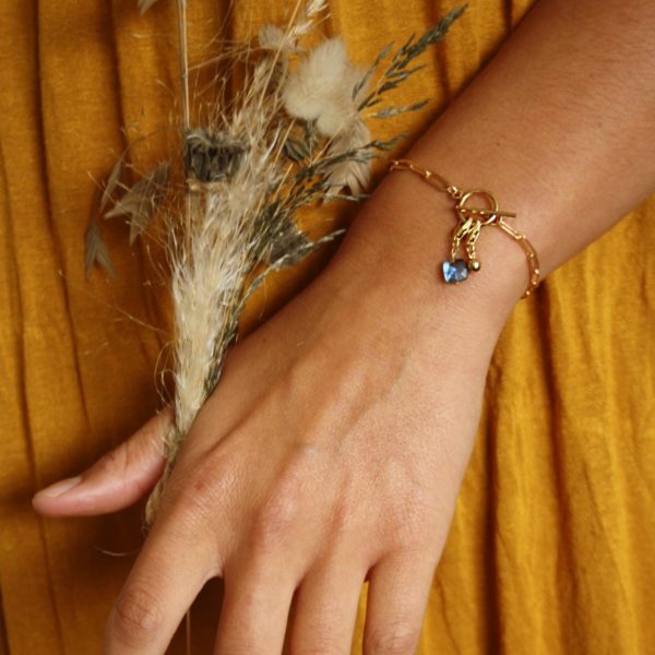 Main de jeune femme tenant un bouquet de fleurs séchées et portant au poignet un bracelet Ambre avec breloques de Tik Tik création